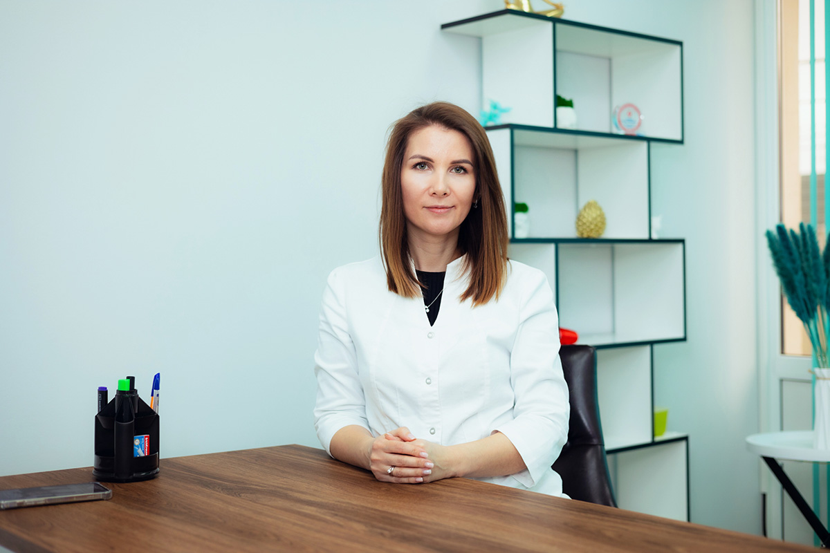 Доктор Калюжная сидит за столом